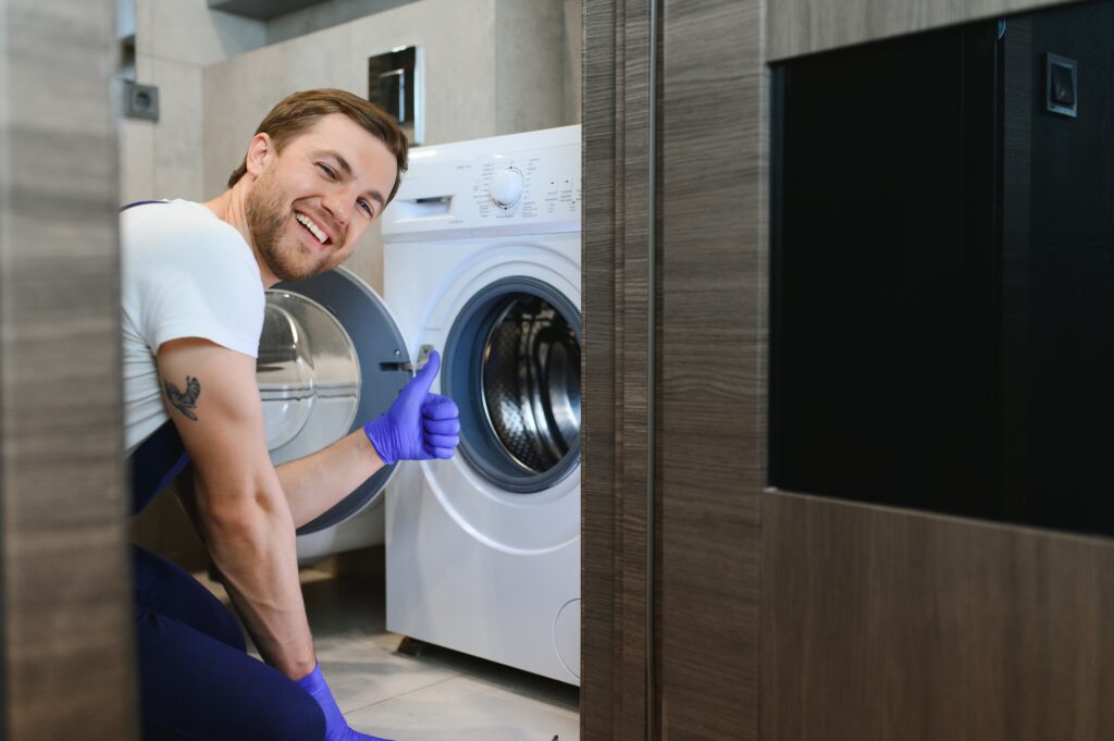 Home working man plumber repairs a washing machine