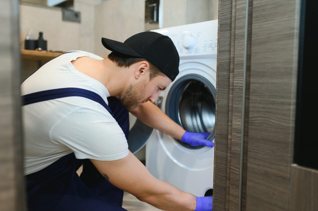 working man plumber repairs a washing machine